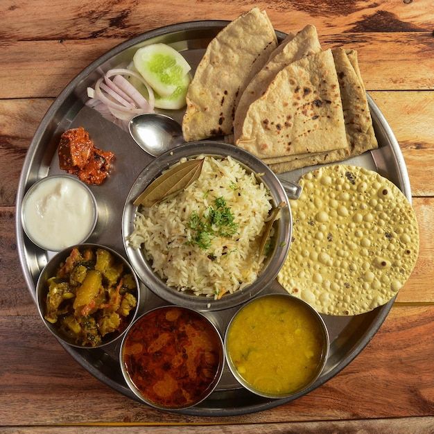veg thali from an indian cuisine food platter consists variety of veggiespaneer dish lentils jeera riceroti sweet dish curd onion etc selective focus premium photo